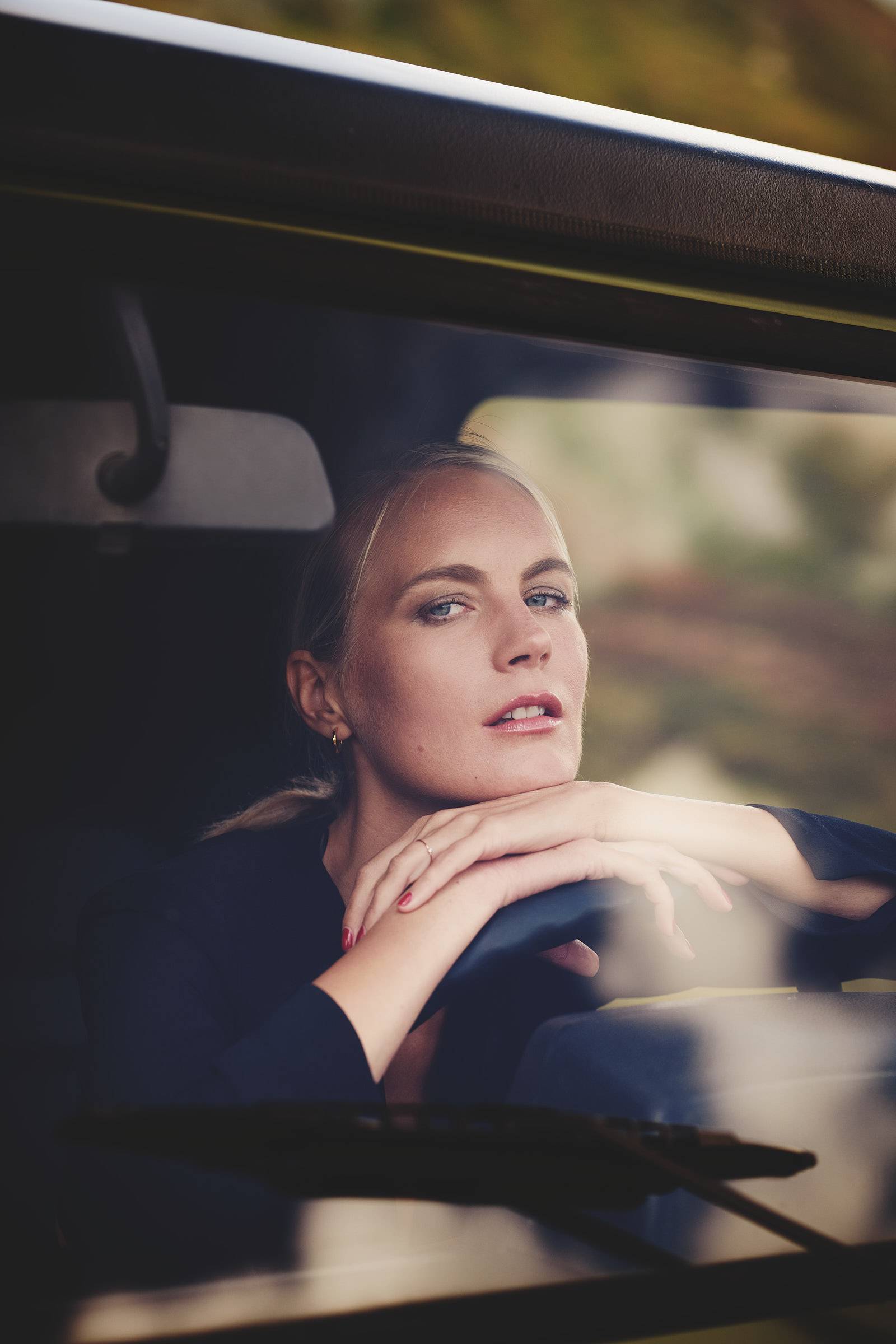 Frau sitzt im Auto hinter dem Lenkrad und schaut in die Kamera