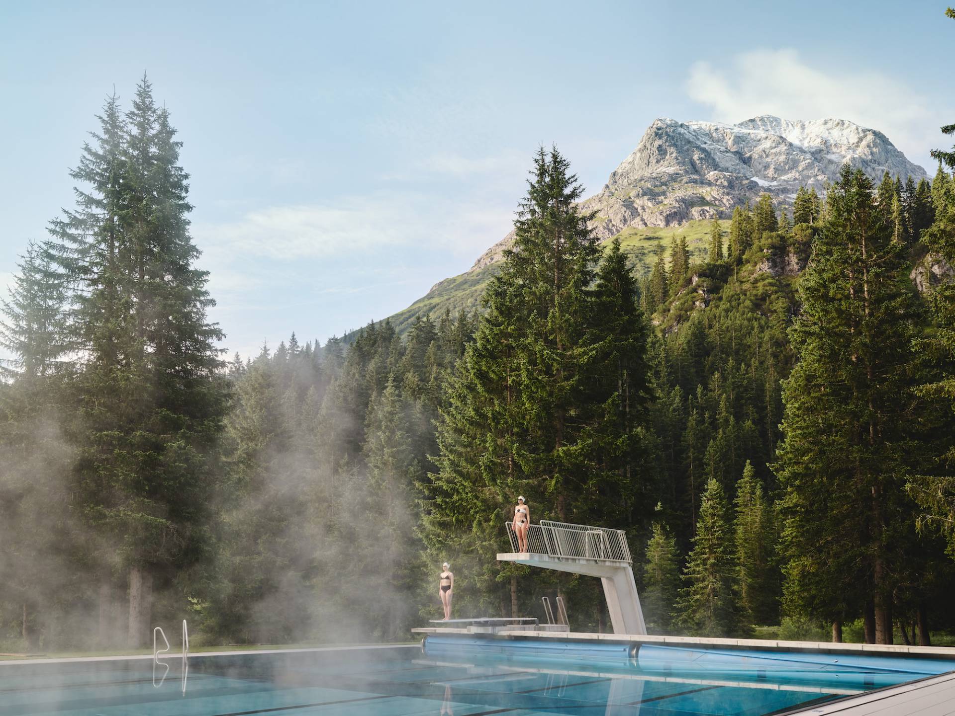 Diving platform at the forest swimming pool with a view of the mountains